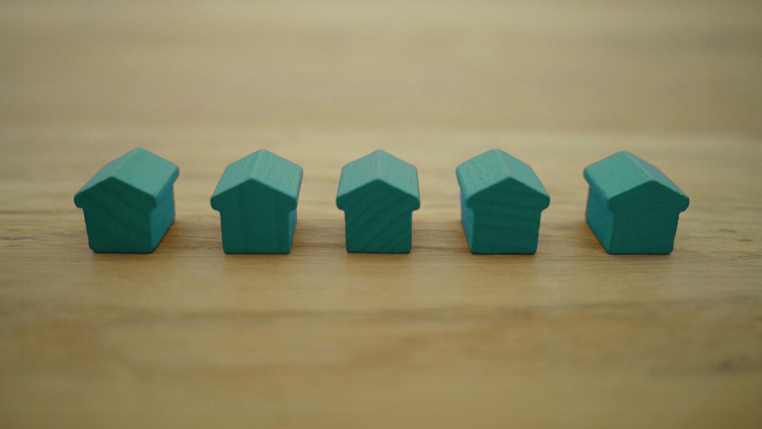 Green model houses on a wooden surface